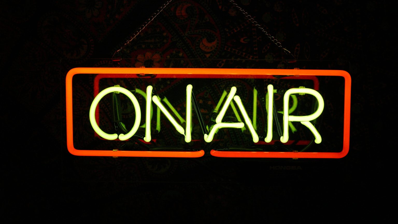 Leuchtschild über einer Tür zu einem Aufnahmestudio beim Film oder Radio mit dem Schriftzug "On Air", der leuchtet