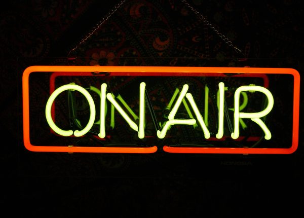 Leuchtschild über einer Tür zu einem Aufnahmestudio beim Film oder Radio mit dem Schriftzug "On Air", der leuchtet