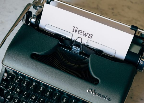 Schreibmaschine mit weissem Blatt Papier, auf dem NEWS steht.
